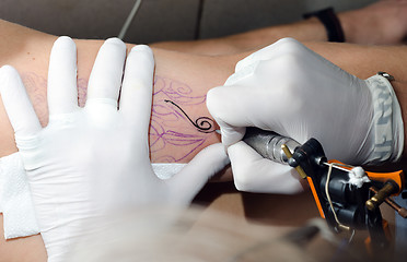 Image showing Tattoo artist makes the tattoo on arm