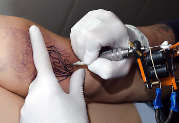 Image showing Tattoo artist makes the tattoo on arm