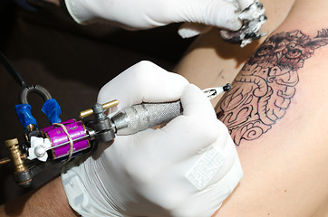 Image showing Tattoo artist makes the tattoo on arm