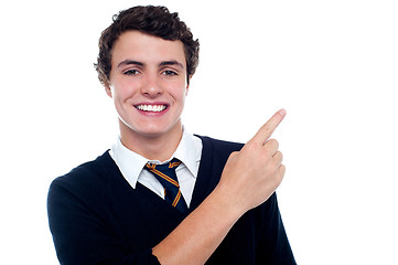Image showing Cheerful schoolboy pointing at copy space area
