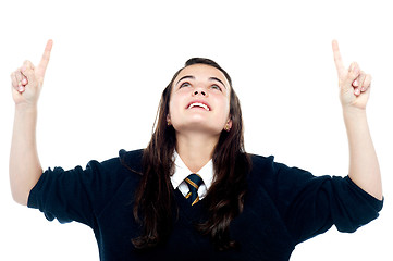 Image showing Excited young teenage girl looking and pointing upwards