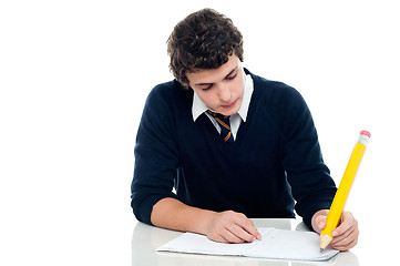 Image showing Young schoolboy taking up his test at school