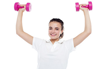 Image showing Smiling girl working out. Dumbbells above her head