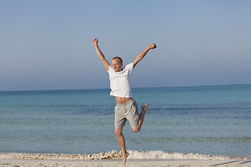 Image showing Cheerful man jumping on the beach laughing Landscape