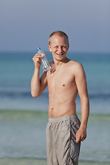 Image showing Man drinking water from a bottle on the beach portrait