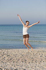 Image showing Cheerful woman jumping laughing at beach portrait