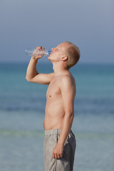 Image showing Man drinking water from a bottle on the beach portrait