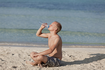 Image showing Man drinking water from a bottle on the beach landscape