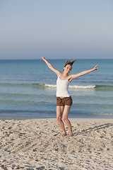 Image showing Cheerful woman jumping laughing at beach portrait