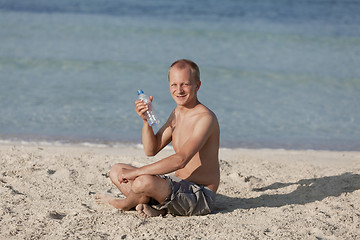 Image showing Man drinking water from a bottle on the beach landscape