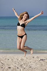 Image showing Woman with bikini jumping happily on the beach portrait