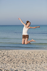 Image showing Cheerful woman jumping laughing at beach portrait