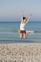 Image showing Cheerful woman jumping laughing at beach portrait