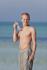 Image showing Man drinking water from a bottle on the beach portrait