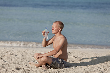 Image showing Man drinking water from a bottle on the beach landscape