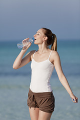 Image showing Woman drinking water from a bottle on the beach portrait