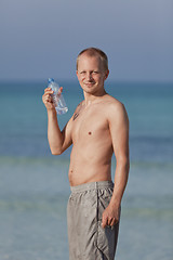 Image showing Man drinking water from a bottle on the beach portrait