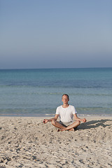 Image showing Man makes yoga sports on the beach portrait