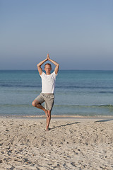 Image showing Man makes yoga sports on the beach portrait