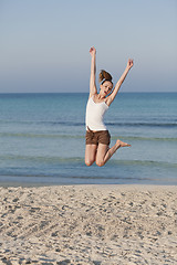 Image showing Cheerful woman jumping laughing at beach portrait