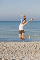 Image showing Cheerful woman jumping laughing at beach portrait