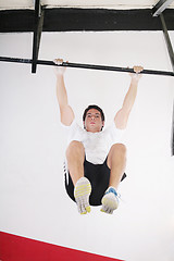 Image showing fit man performing pull ups in a bar