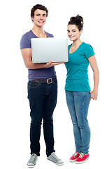 Image showing Teen friends holding laptop. Full length shot