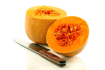 Image showing Two halves of a ripe pumpkin and a table knife.