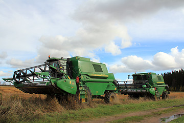 Image showing Two green combine harvesters by wet field