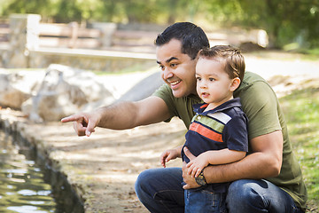 Image showing Hispanic Father Points with Mixed Race Son at the Park