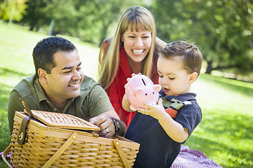 Image showing Mixed Race Couple Give Their Son a Piggy Bank at the Park