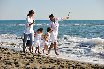 Image showing happy family playing with dog on beach