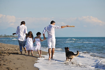 Image showing happy family playing with dog on beach