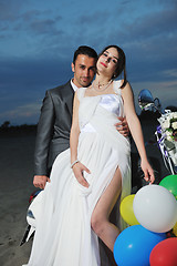 Image showing just married couple on the beach ride white scooter