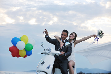 Image showing just married couple on the beach ride white scooter