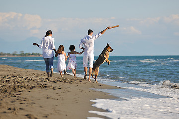 Image showing happy family playing with dog on beach