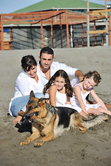 Image showing happy family playing with dog on beach