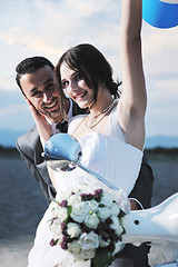 Image showing just married couple on the beach ride white scooter