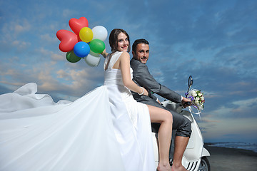 Image showing just married couple on the beach ride white scooter