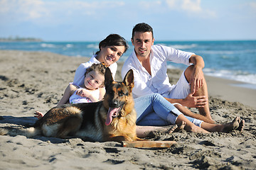 Image showing happy family playing with dog on beach