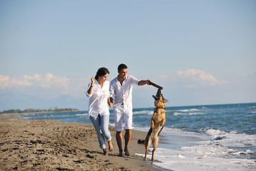 Image showing happy family playing with dog on beach