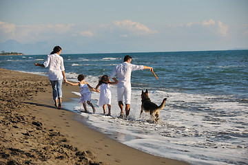 Image showing happy family playing with dog on beach