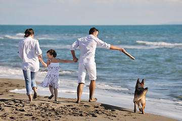 Image showing happy family playing with dog on beach