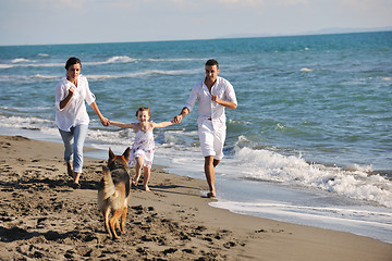 Image showing happy family playing with dog on beach