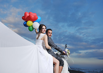 Image showing just married couple on the beach ride white scooter