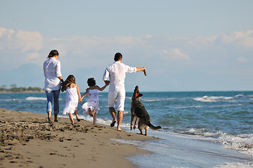 Image showing happy family playing with dog on beach