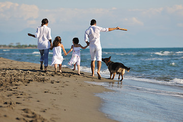 Image showing happy family playing with dog on beach