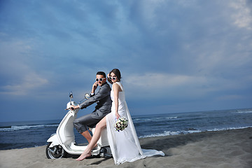 Image showing just married couple on the beach ride white scooter