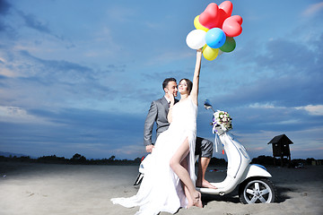 Image showing just married couple on the beach ride white scooter