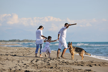 Image showing happy family playing with dog on beach